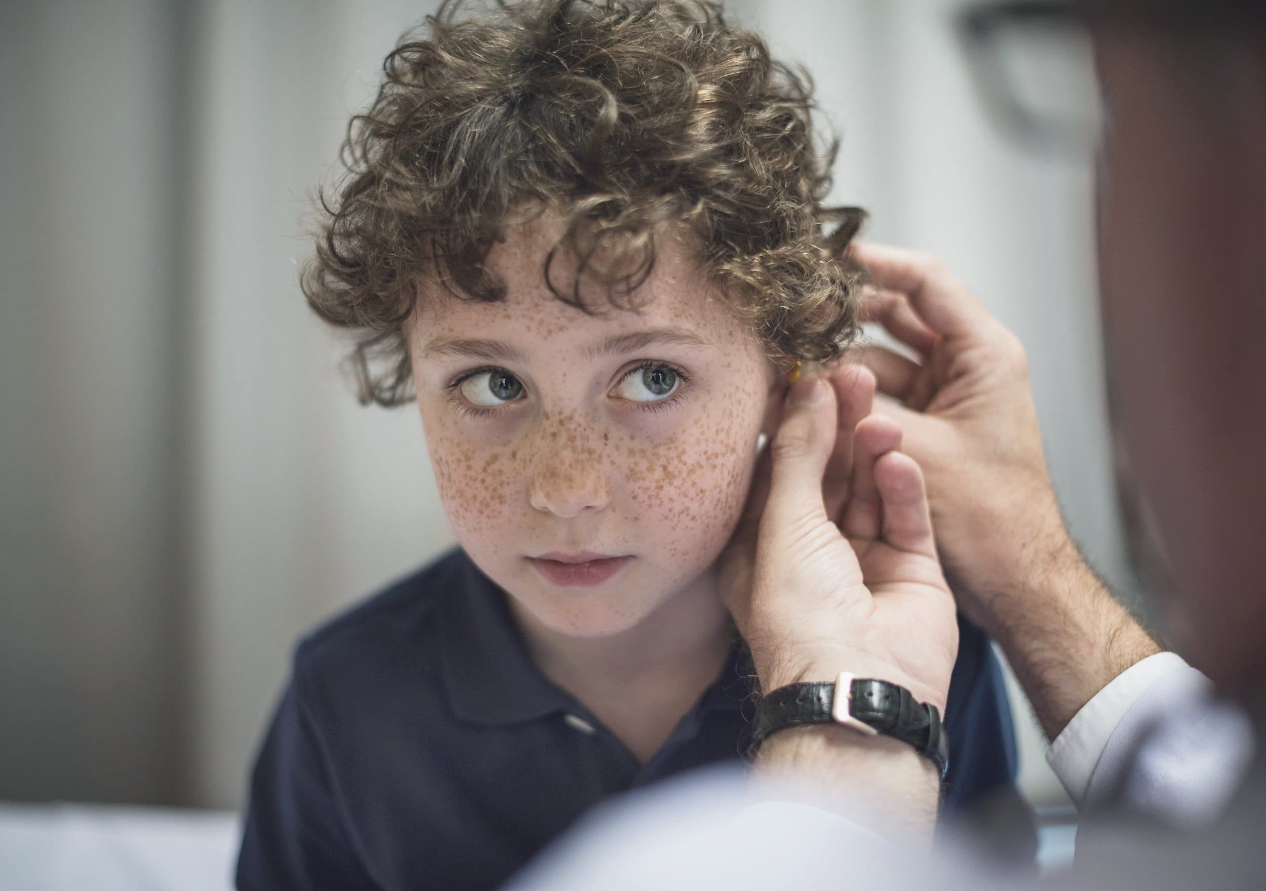 GP examining a young child's ear during a private children's GP appointment.