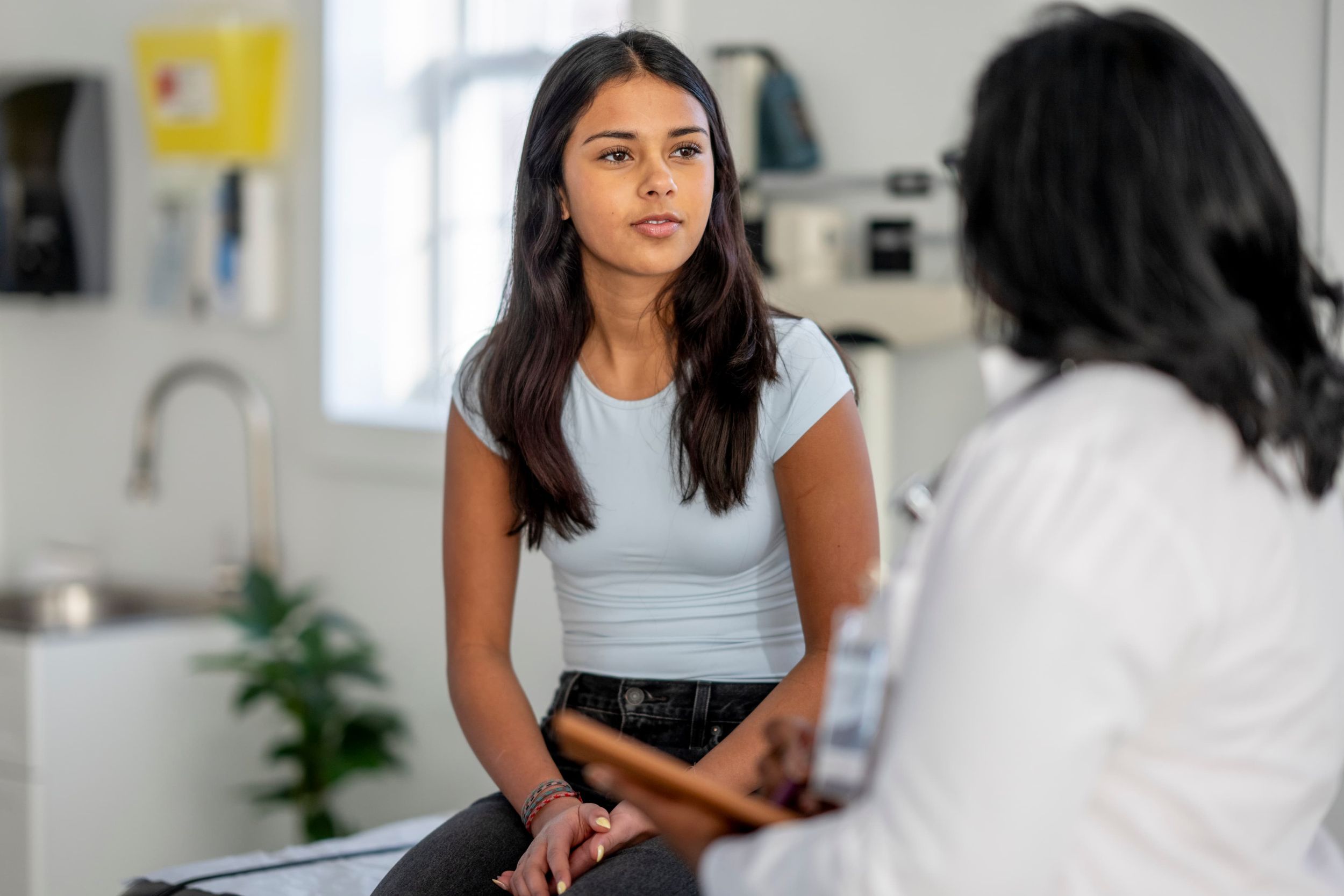 Young woman speaking with a private GP during a face-to-face consultation at Enigma Healthcare.
